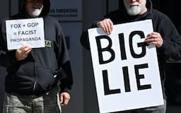 米東部デラウェア州の裁判所前でフォックスに対して「大きな嘘」と書いたものを掲げて抗議する人々（4月18日）=ロイター